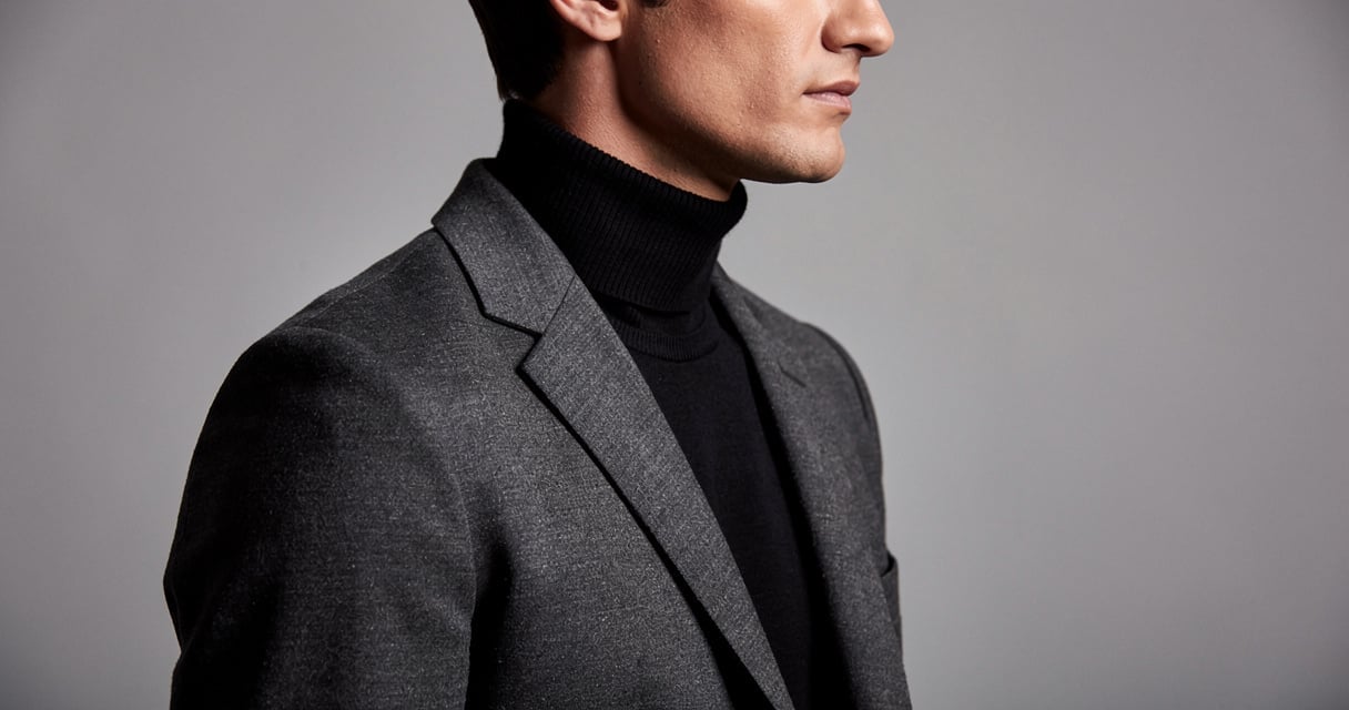 Homme en col roulé noir fin sous un blazer gris anthracite, allure classique et intemporelle