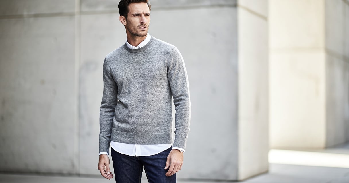 Homme portant un pull gris chiné col rond avec chemise blanche et jean indigo